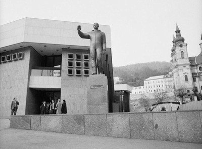 Černobílá fotografie sochy před budovou Vřídelní kolonády